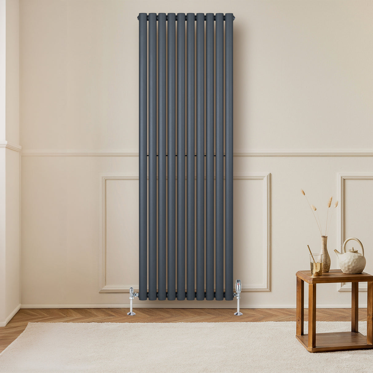Radiateur à colonnes ovales gris anthracite, 1800 x 600 mm, installé sur un mur clair, avec un sol en bois et une table en bois à proximité