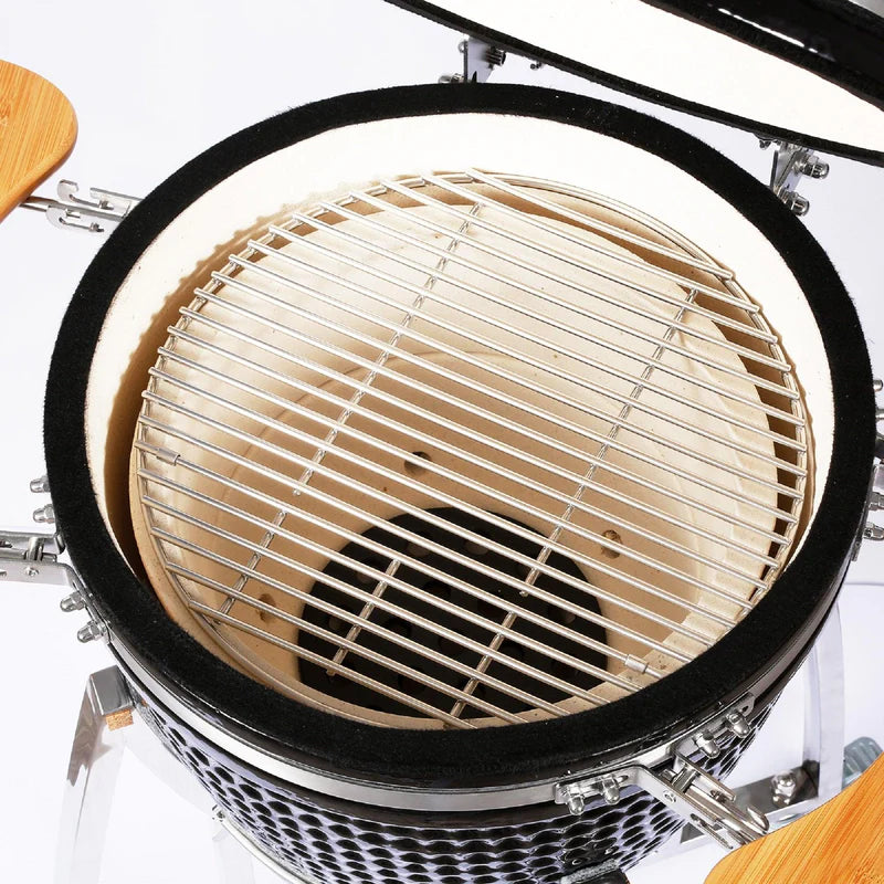 Grille en acier inoxydable à l'intérieur d'un barbecue au charbon de bois Kamado, avec un design circulaire et des bords en céramique noire