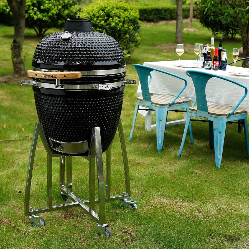 Barbecue au charbon de bois Kamado noir, 53,3 cm, avec support en acier inoxydable et table de jardin en arrière-plan