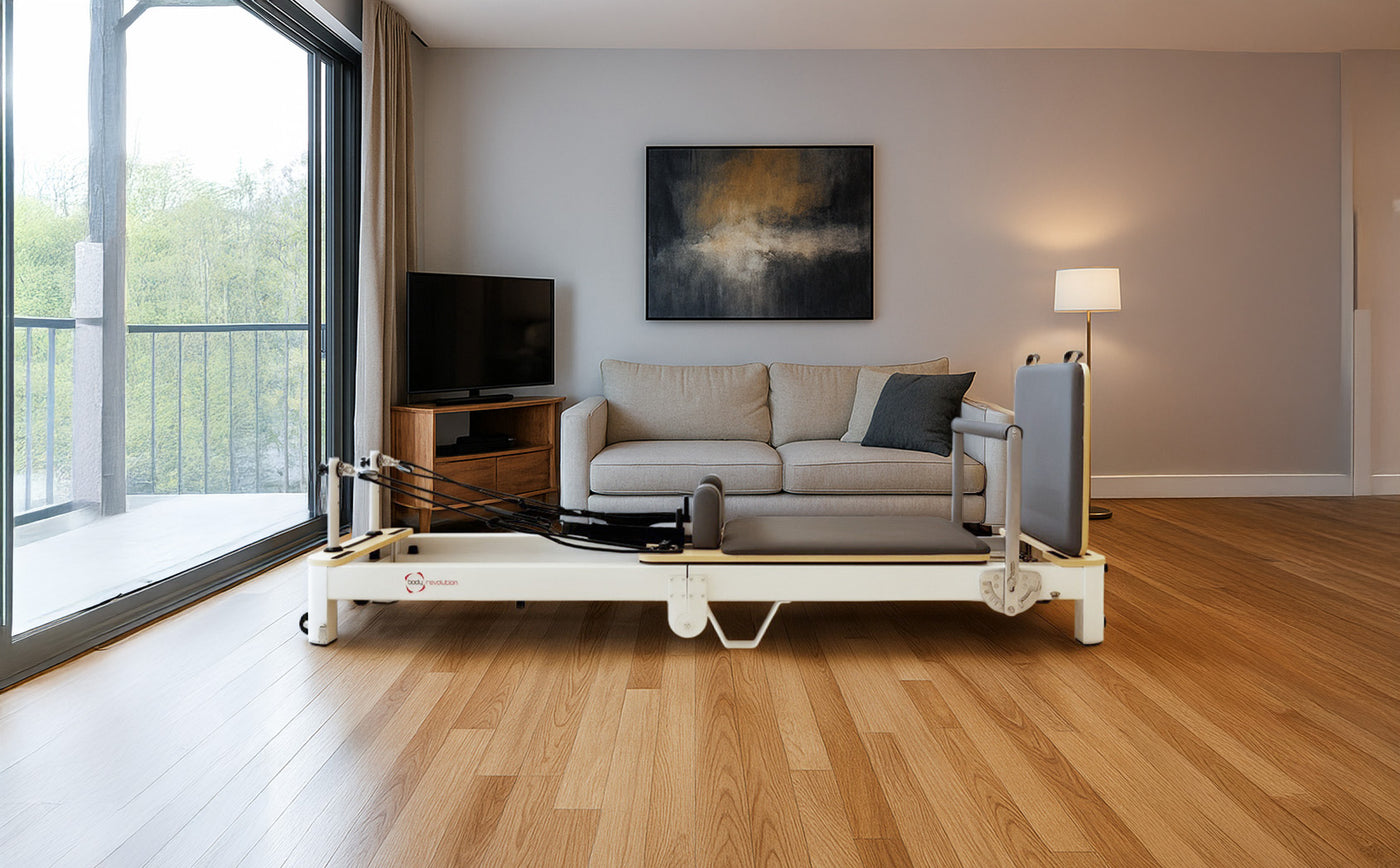 Lit médical ajustable en métal blanc avec matelas gris, placé dans un salon moderne avec canapé et télévision, lumière naturelle