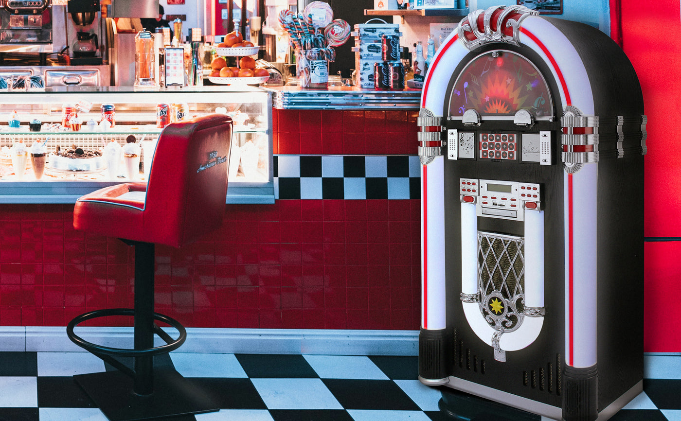 Jukebox vintage aux couleurs vives, noir et rouge, avec lumières LED, placé près d'un bar rétro à carreaux noirs et blancs