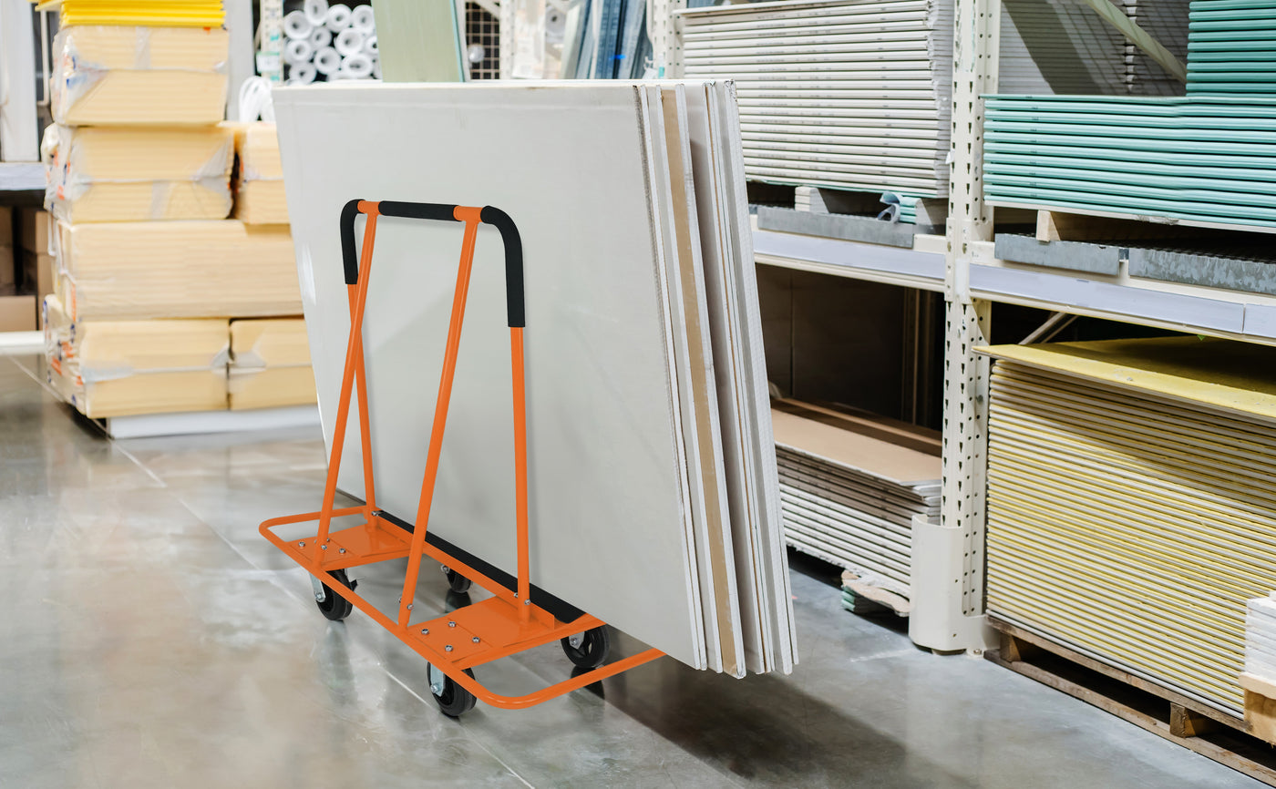 Chariot orange transportant des panneaux de construction en bois, sur un sol en béton, entouré de matériaux de construction variés