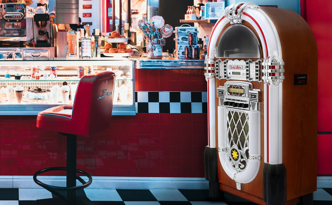 Jukebox vintage en bois avec des accents chromés, situé dans un diner rétro aux murs rouges et noir, avec des sièges en cuir rouge