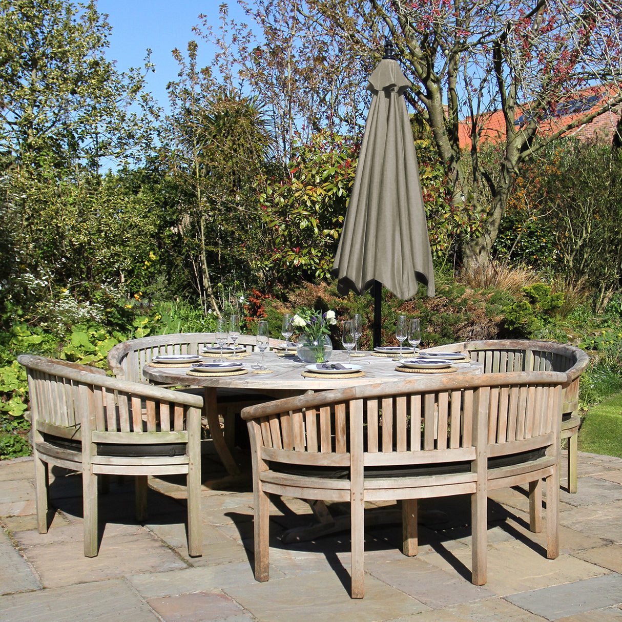Parasol déporté beige de 3 m, installé au-dessus d'une table en bois entourée de chaises, dans un jardin verdoyant et ensoleillé