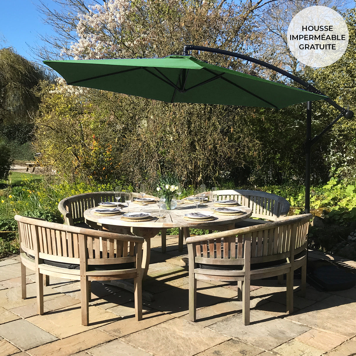 Parasol déporté de 3 m en vert, installé au-dessus d'une table en bois entourée de chaises, dans un jardin ensoleillé