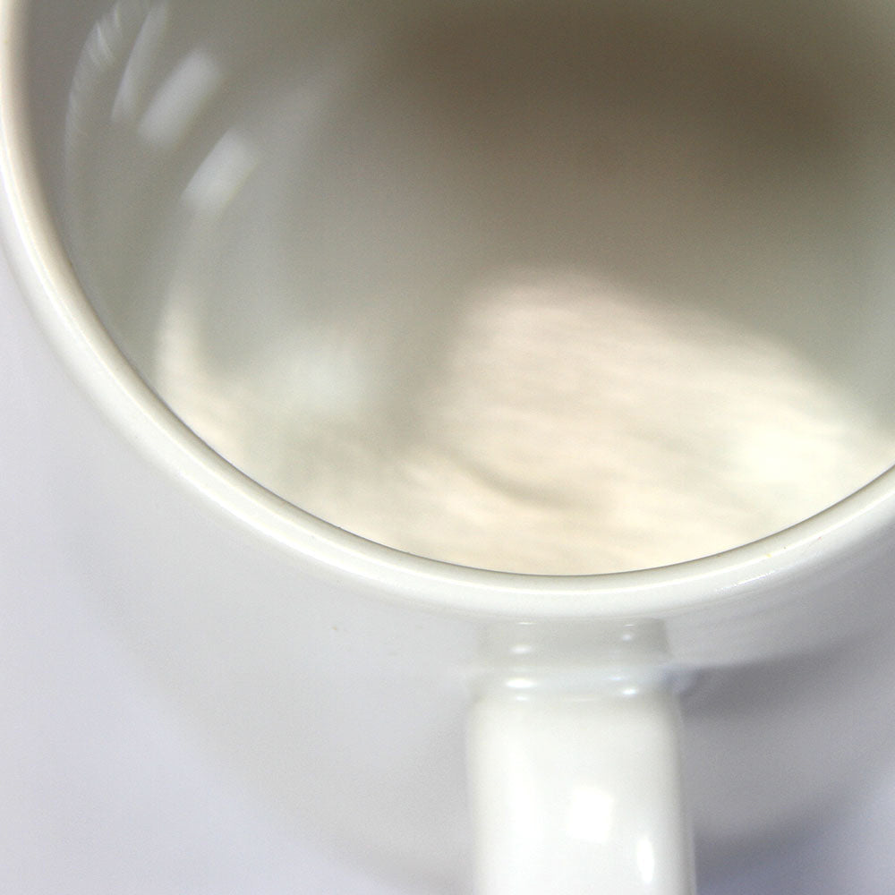 Tasse blanche en céramique lisse, idéale pour la sublimation, avec une anse ergonomique et une finition brillante, présentée sur un fond neutre