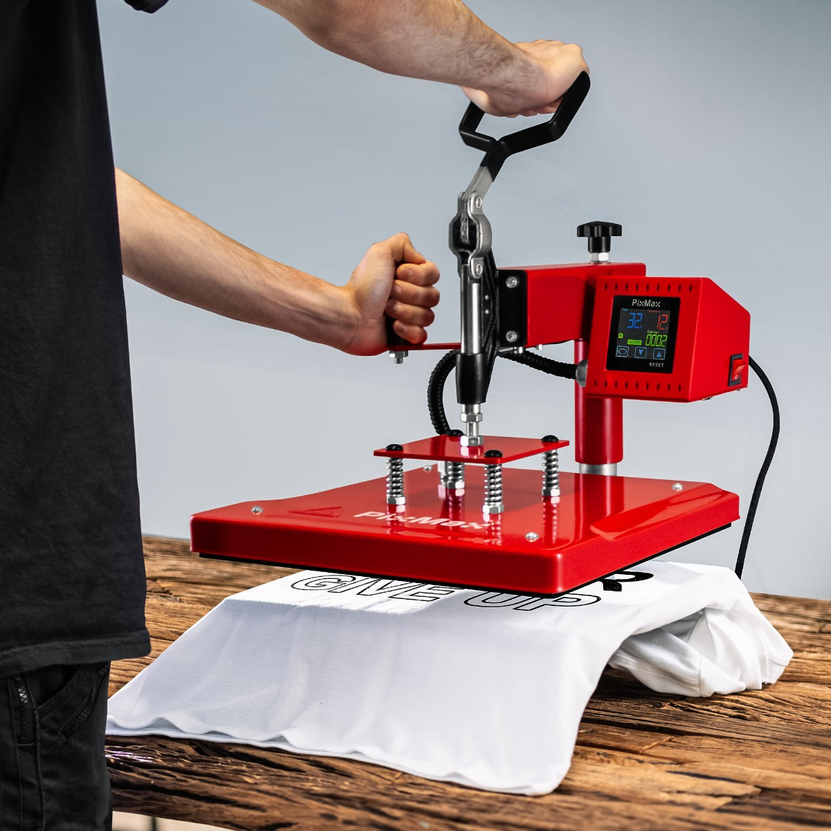 Presse à chaud rouge de 38 cm en action sur un t-shirt blanc, avec écran numérique et poignée ergonomique pour un usage facile
