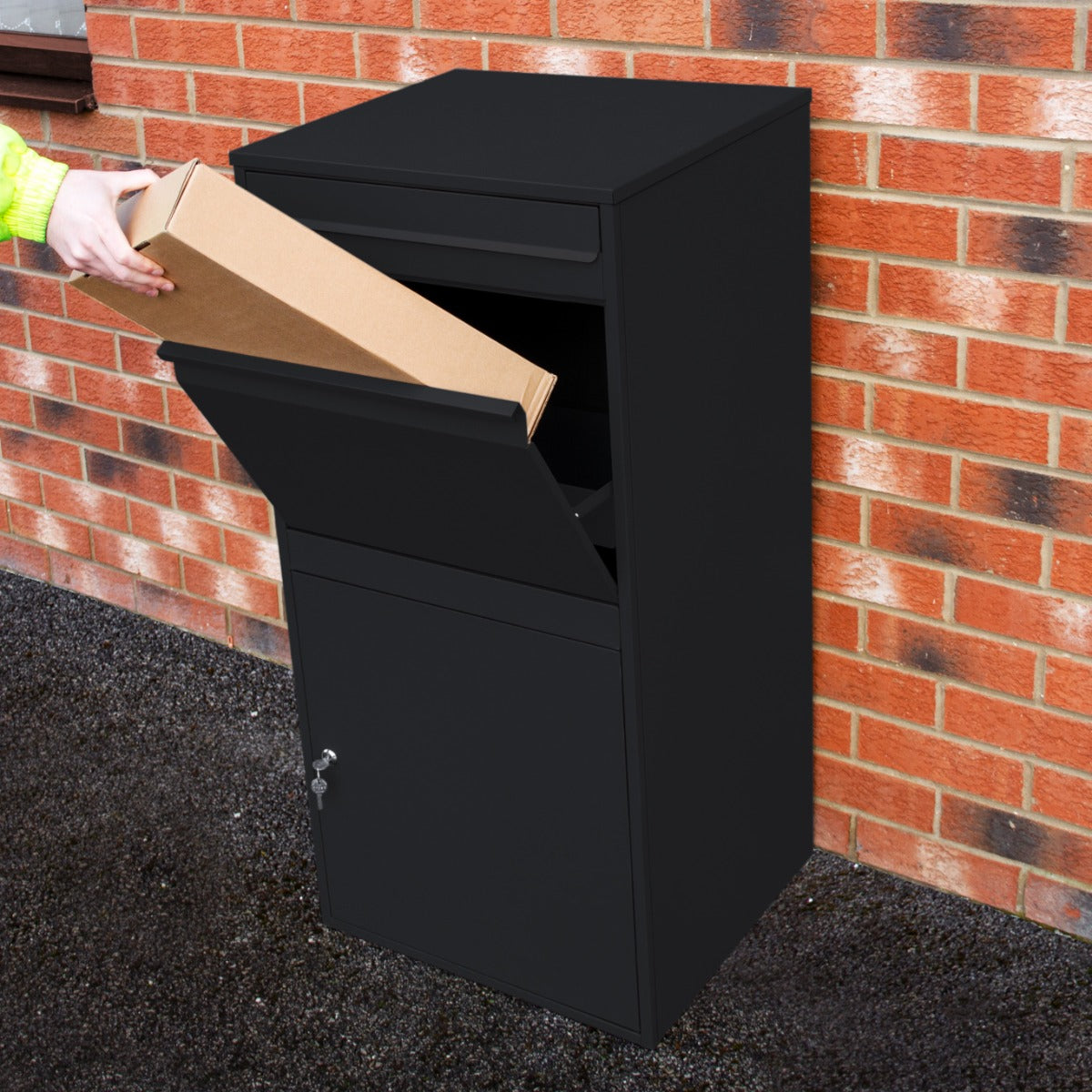 Boîte à colis XL anti-vol noire, en métal, avec une fente pour colis et un compartiment sécurisé, placée contre un mur en briques
