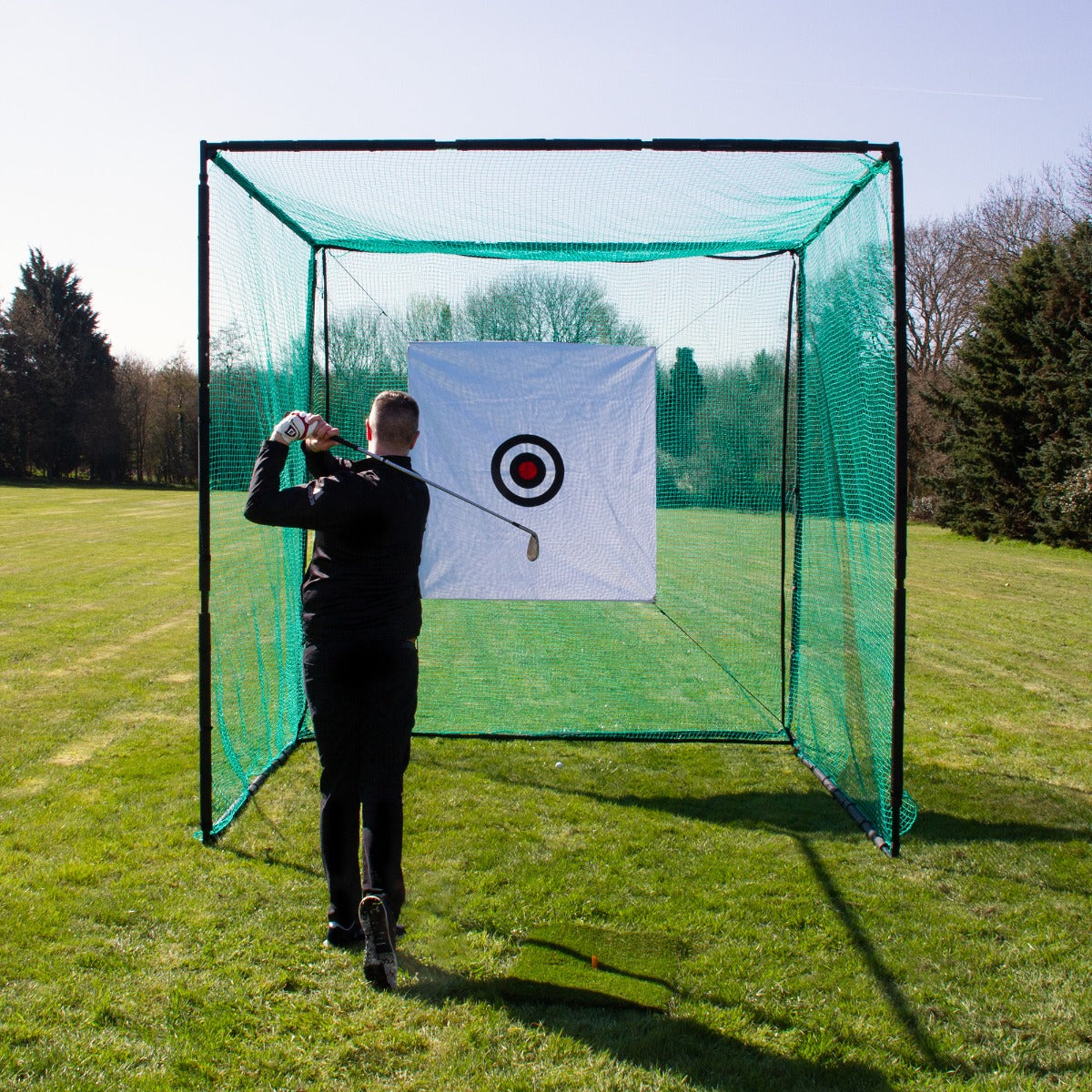 Cage d'entraînement de golf en filet vert avec une cible blanche et rouge, utilisée sur un terrain ensoleillé pour perfectionner les coups