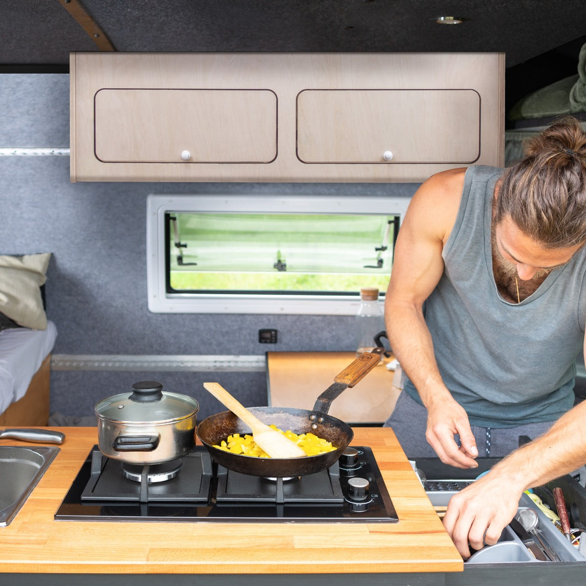 Armoire de rangement en bois clair pour camping-car, avec deux tiroirs, intégrée à une cuisine moderne et fonctionnelle