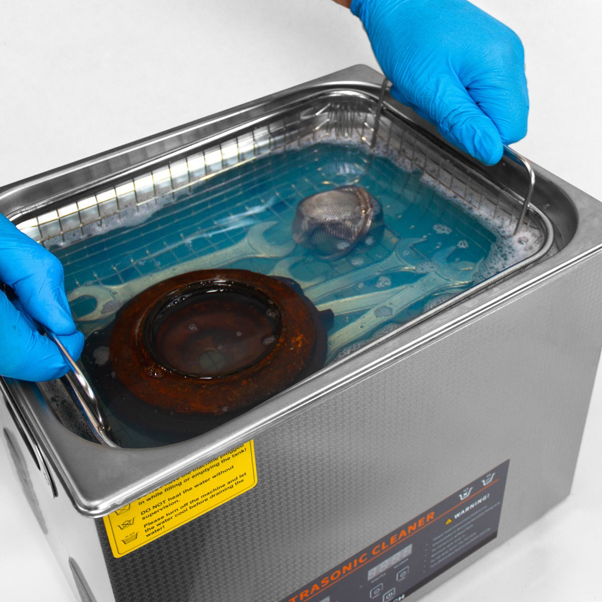 Nettoyeur ultrasonique T-Mech de 30 L avec des gants bleus, plongeant un objet dans un liquide bleu clair, cuve en acier inoxydable brillante