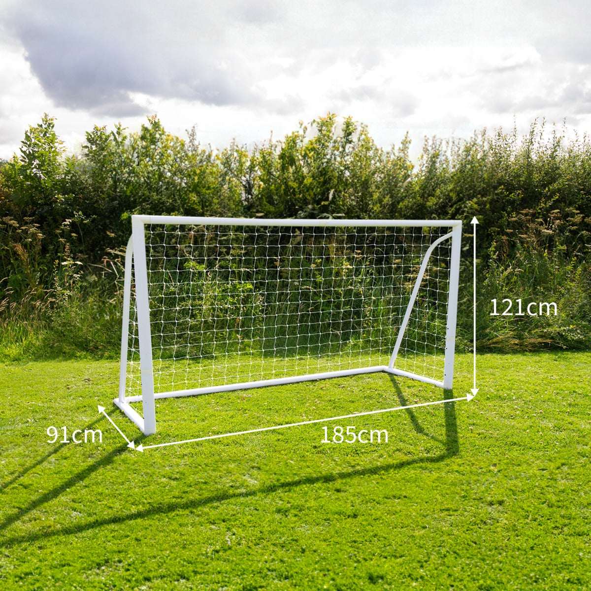 But de football blanc de 1,8 x 1,2 m avec filet, installé sur un terrain vert, entouré de verdure et sous un ciel nuageux