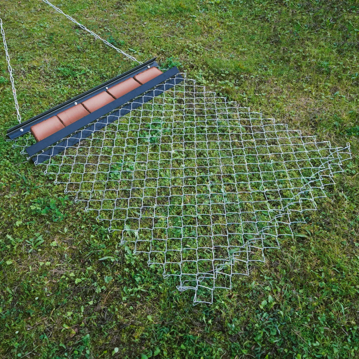 Herse traînée en acier de 1,2 m x 1,5 m, avec un cadre noir et un maillage métallique, posée sur un sol herbeux verdoyant