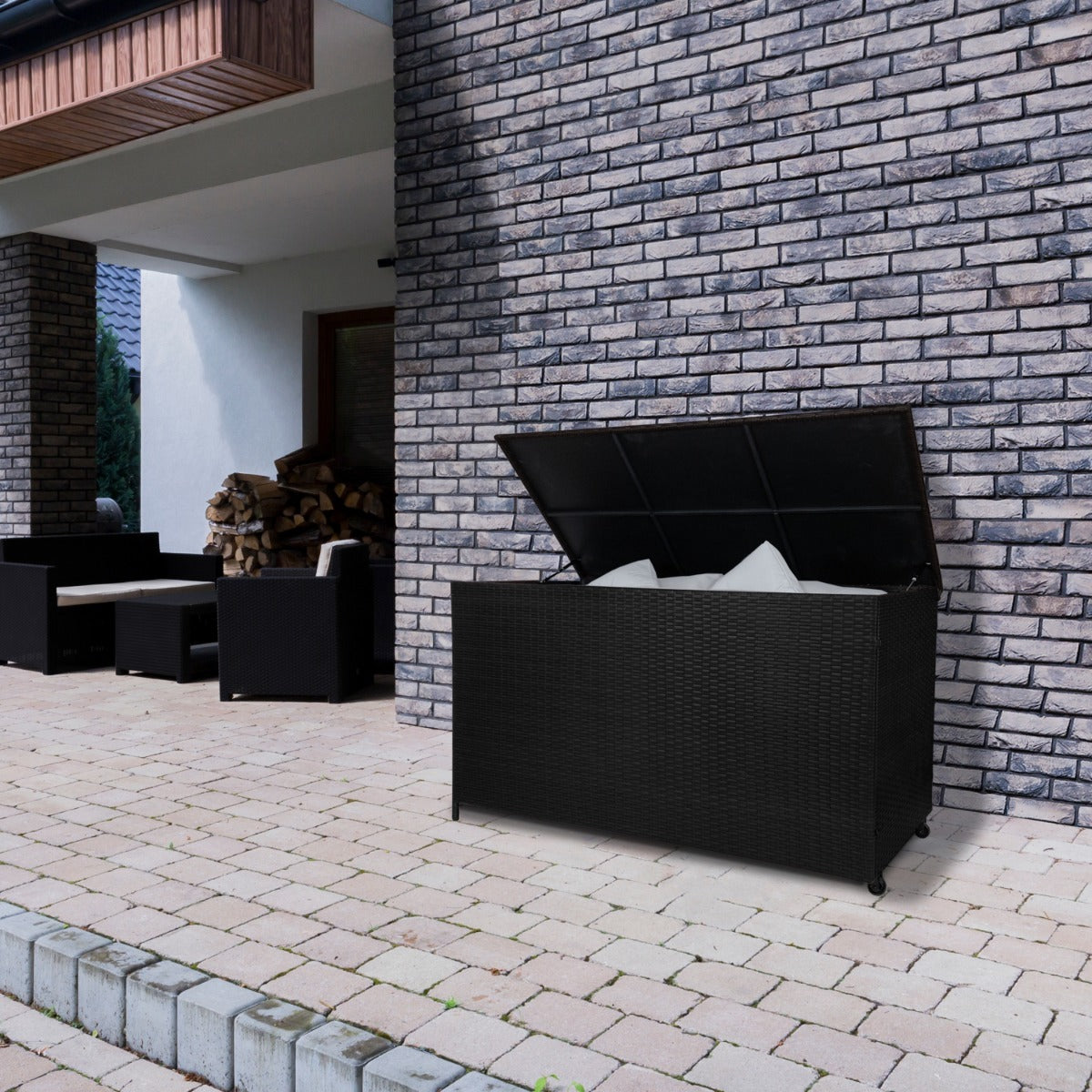 Coffre de rangement extérieur en rotin noir de 582 L, avec un couvercle ouvert, sur un patio en briques, entouré de meubles en rotin