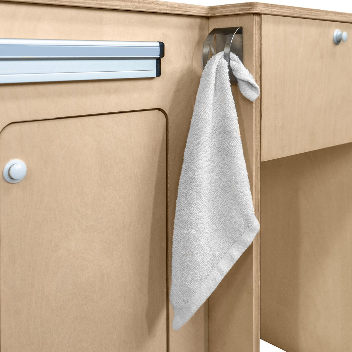 Meuble de cuisine en contreplaqué clair avec un torchon gris accroché, montrant une texture lisse et un design fonctionnel pour camping-car