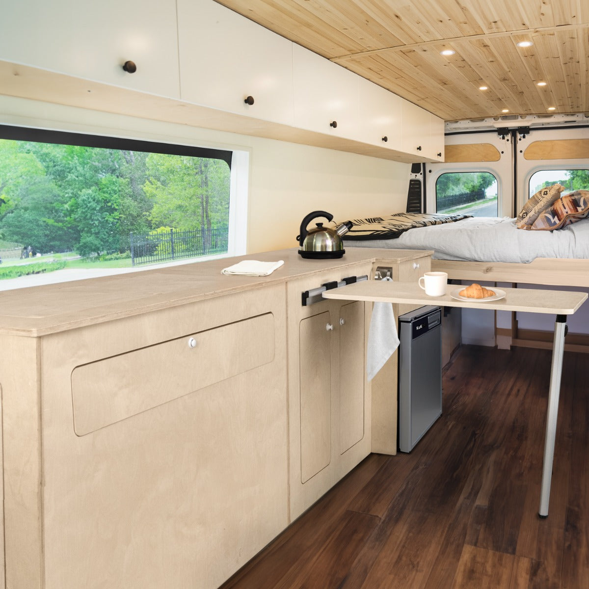 Mobilier de cuisine en contreplaqué clair avec frigo argenté, plan de travail moderne, ambiance chaleureuse et fonctionnelle pour camping-car