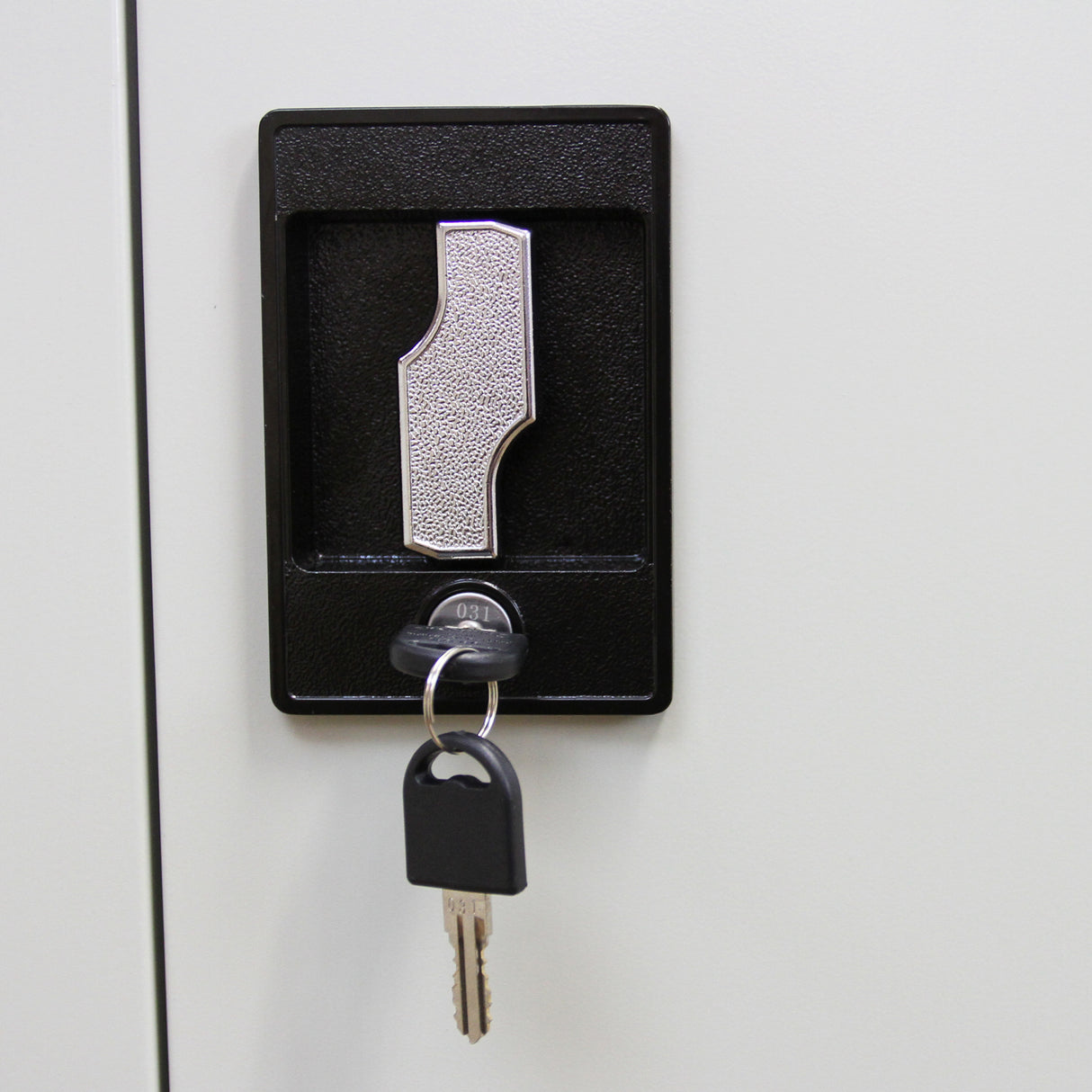 Serrure en métal noir avec clé, sur une armoire de classement métallique en acier gris clair, ajoutant sécurité et fonctionnalité
