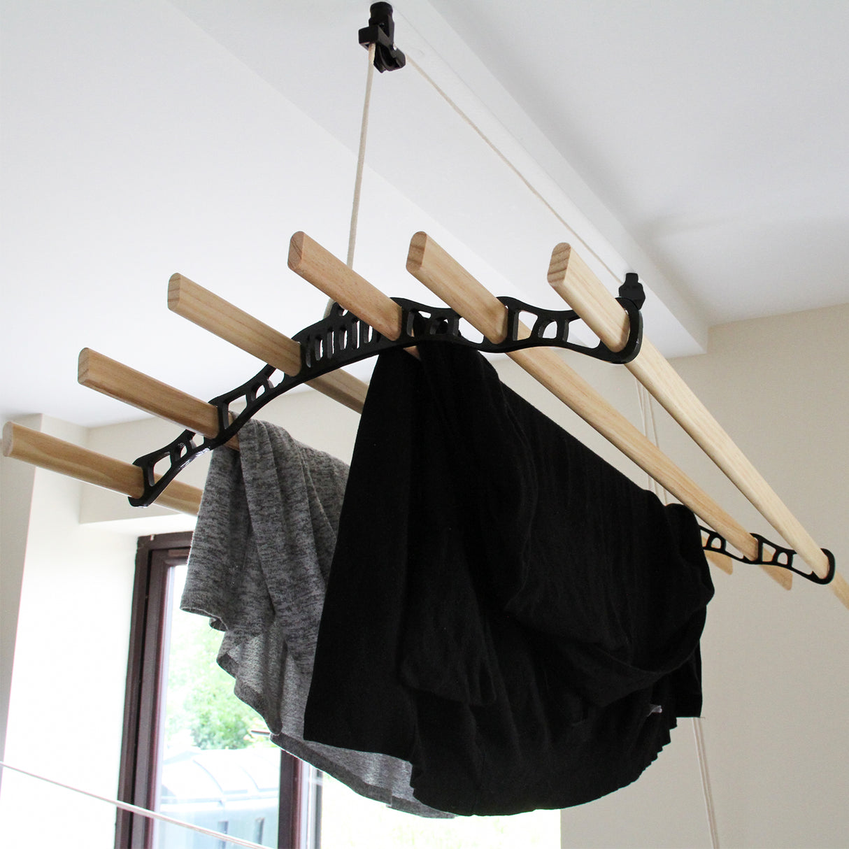 Étendoir à linge suspendu noir de 1,8 m avec des barres en bois, portant des vêtements sombres et légers, suspendu au plafond
