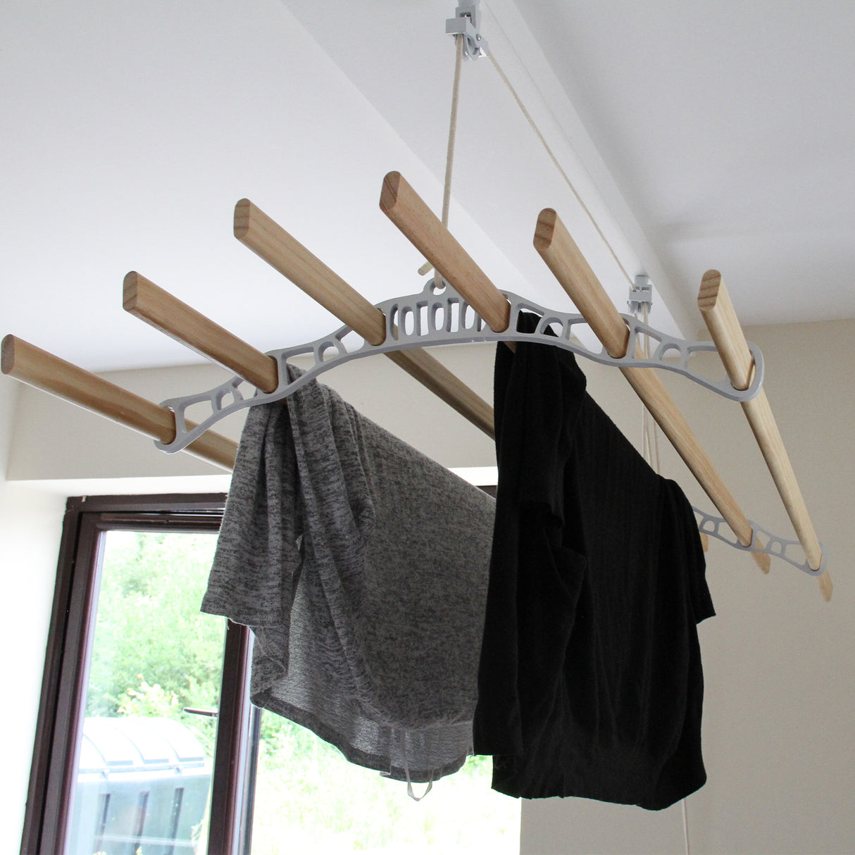 Étendoir à linge suspendu de 1,4 m, structure blanche en plastique avec barres en bois, vêtements gris et noir accrochés, design moderne
