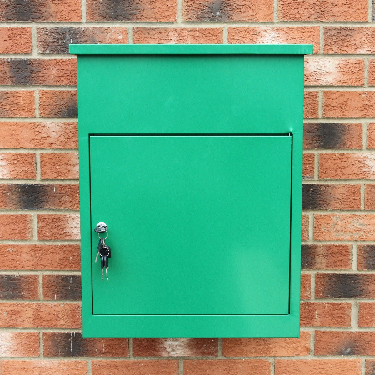 Boîte à colis verte en métal, avec une finition lisse, serrure et clé, fixée sur un mur en briques rouges texturées