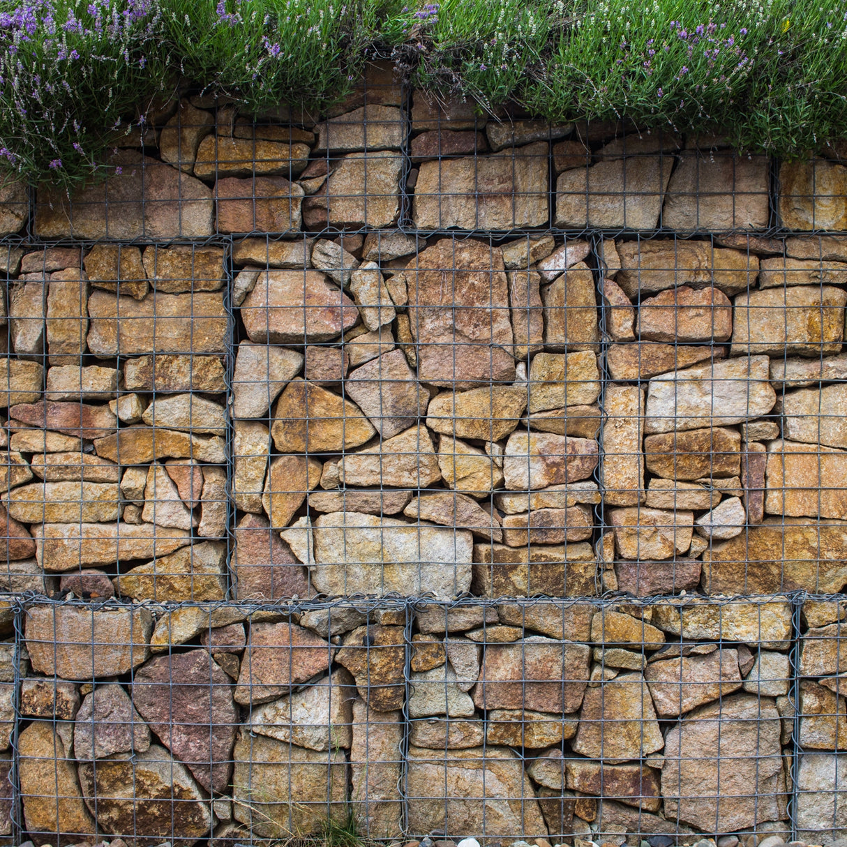 Paniers de gabions en métal, remplis de pierres naturelles aux teintes beige et marron, créant une structure solide et esthétique