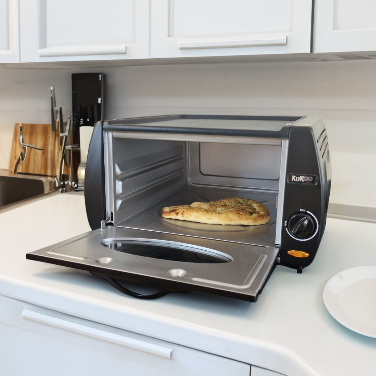 Mini four Tandoor KuKoo en acier inoxydable, avec une porte ouverte révélant un pain doré sur une grille, idéal pour la cuisson rapide