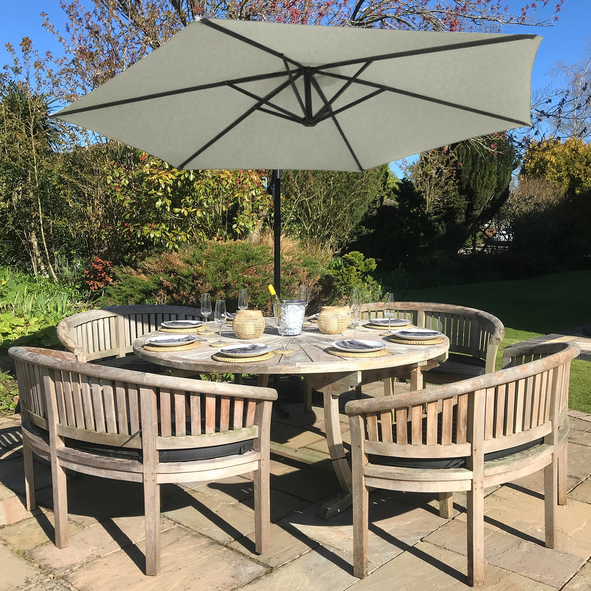 Parasol déporté de 3 m en crème, installé au-dessus d'une table en bois avec des chaises assorties dans un jardin verdoyant