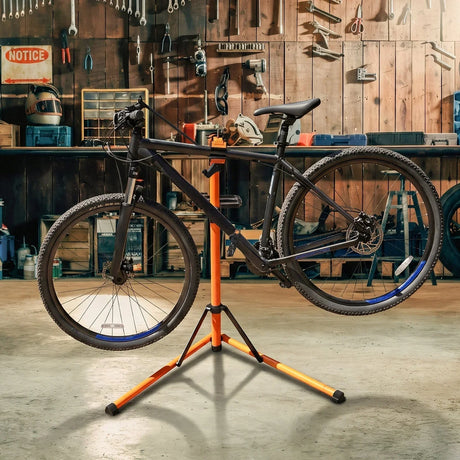 Support de réparation pour vélo noir sur un socle orange, avec un fond d'atelier en bois et outils suspendus, prêt à l'utilisation