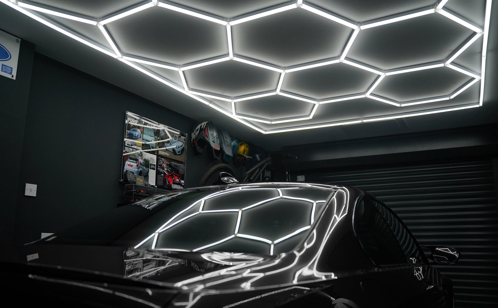 Plafonnier hexagonal moderne en néon blanc illuminant un garage, avec un sol noir brillant et des outils de garage en arrière-plan