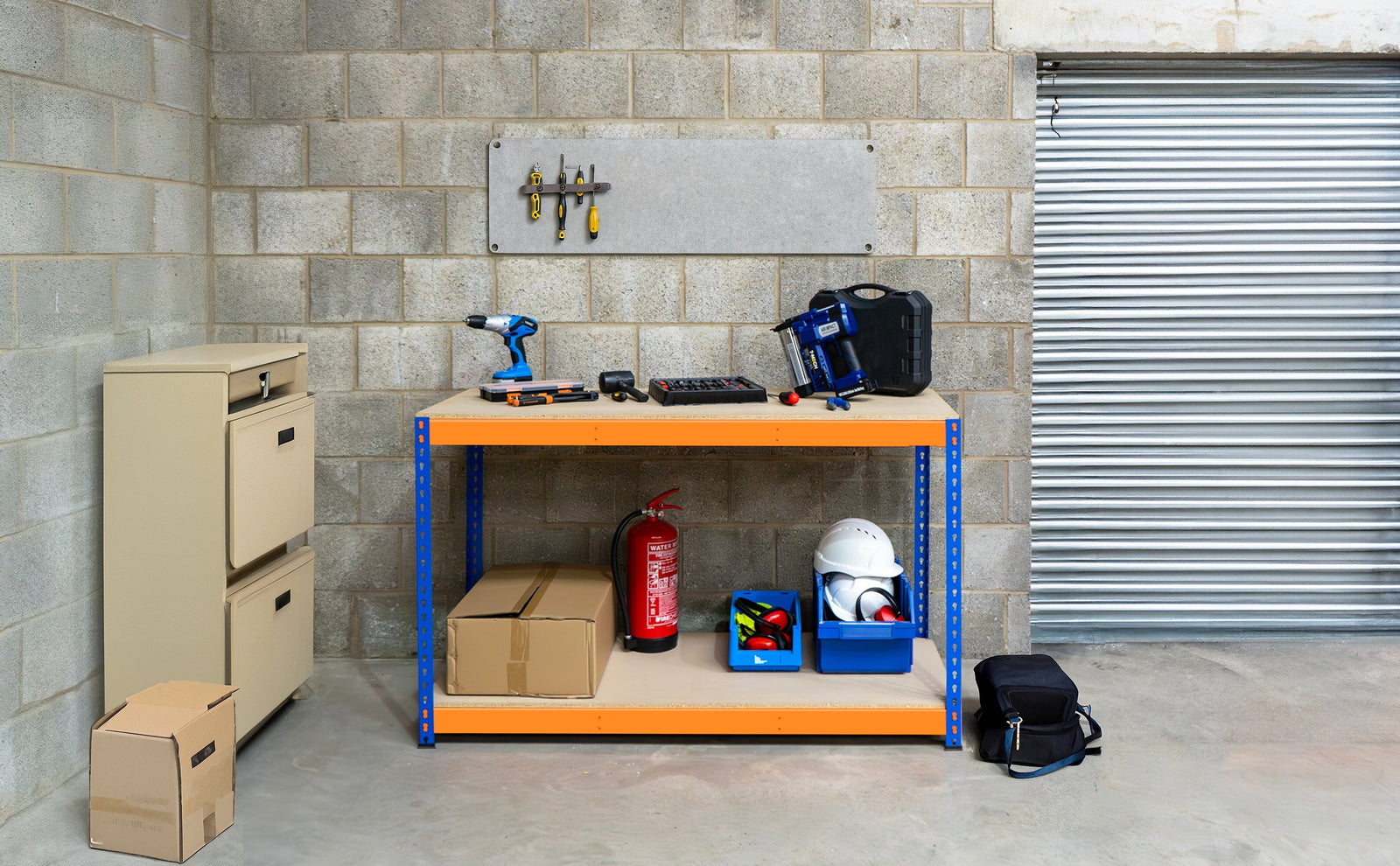 Établi de travail orange avec outils, boîtes de rangement bleues, casques et matériel de bricolage sur fond de mur en béton gris