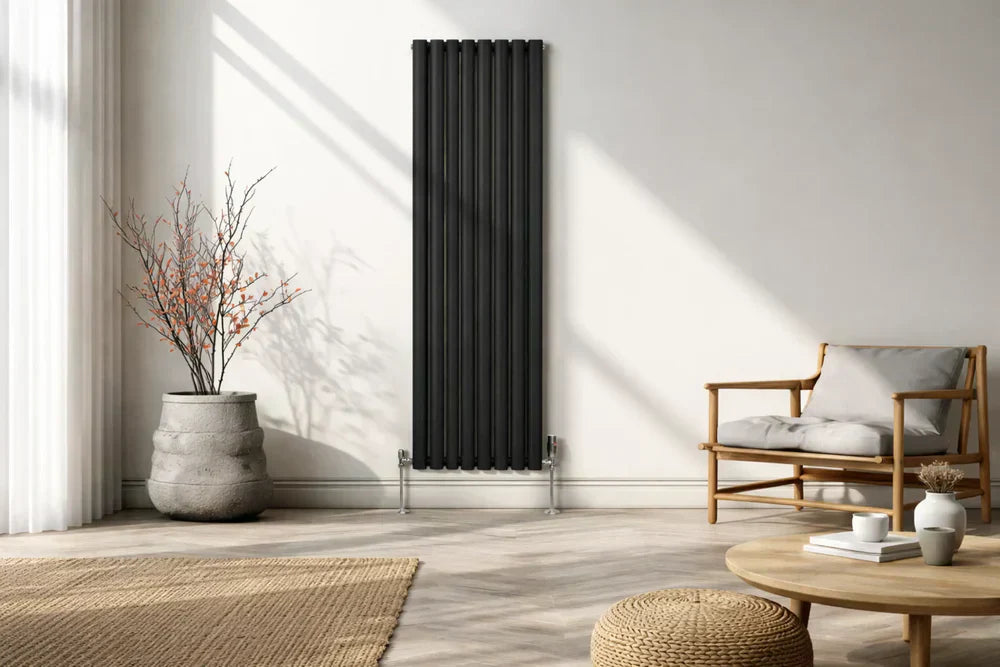 Radiateur à colonnes noir élégant, installé dans un intérieur moderne avec un sol en bois, un fauteuil en rotin et une plante décorative