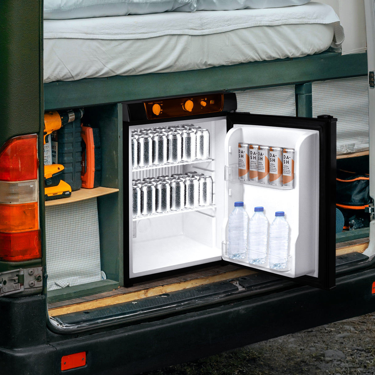 Frigo trimixte noir de 43 L ouvert, avec des bouteilles d'eau et des canettes, installé dans un camping-car sur fond de bois naturel