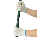 Niveleur de pelouse vert avec manche extensible de 100 cm, tenu par des mains gantées en tissu beige, offrant une prise confortable et sécurisée
