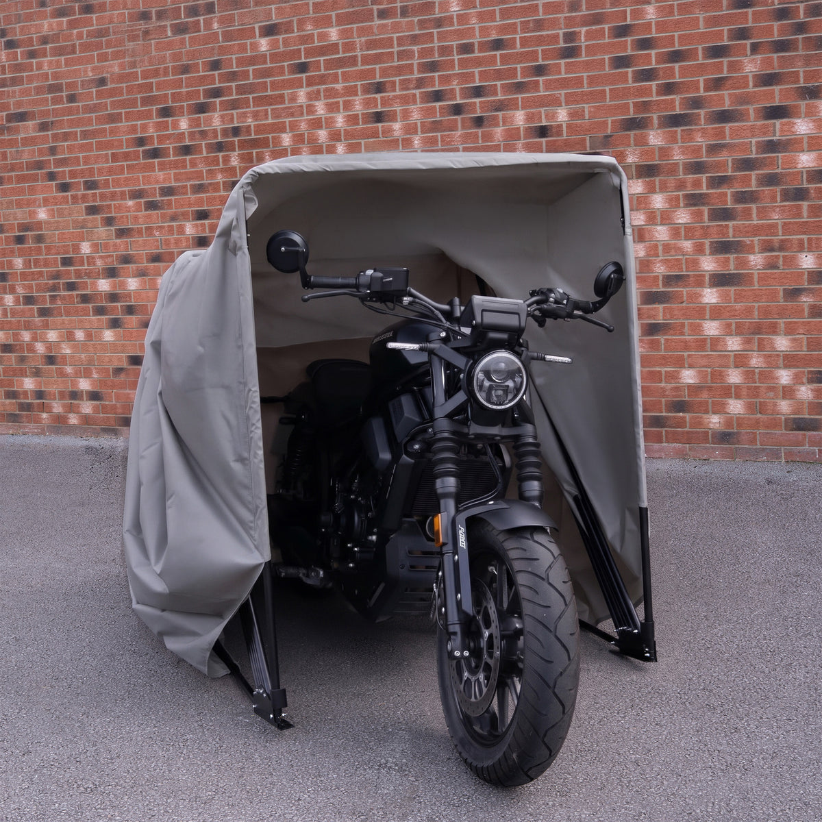 Tente de rangement moto grise, avec une structure en métal, protégeant une moto noire contre les intempéries et la poussière