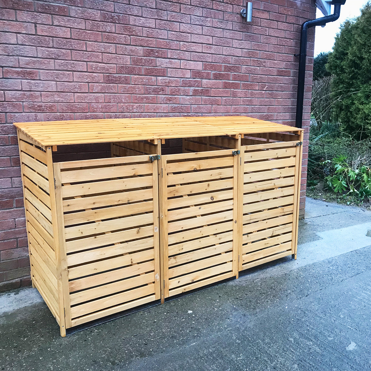 Cache-poubelle triple en bois clair avec lattes horizontales, finition lisse, conçu pour un rangement extérieur élégant et pratique