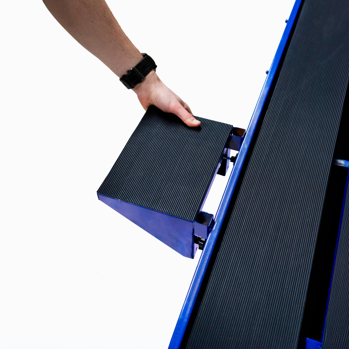 Main d'homme tenant un bloc noir texturé, adapté à une scie de carrelage sur table, avec des surfaces lisses et robustes