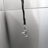 Crochet en métal brillant suspendu par une corde noire, avec un fond en inox lisse et réfléchissant, idéal pour la baignoire de toilettage