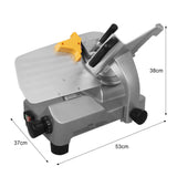 Trancheuse de viande KuKoo en métal argenté, avec un plateau en acier inoxydable, un guide de coupe orange et des dimensions de 53 cm x 37 cm x 38 cm