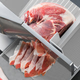 Trancheuse de viande KuKoo en acier inoxydable, avec un bloc de viande rouge et des tranches de jambon rose sur un fond gris