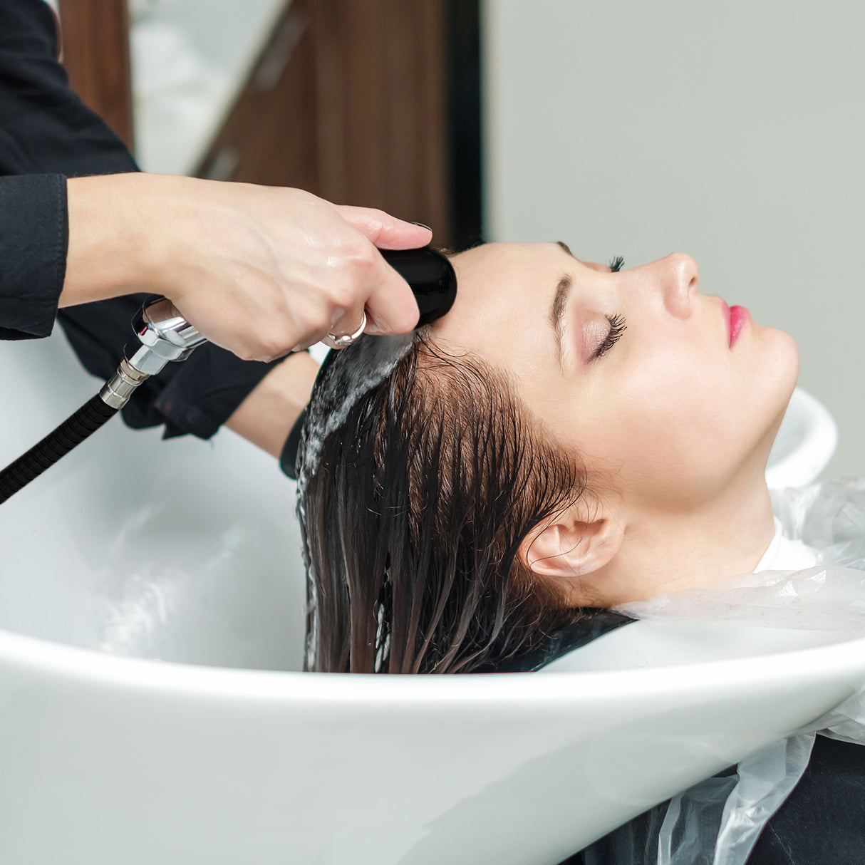 Fauteuil de coiffure blanc avec lavabo, une femme reçoit un lavage de cheveux, ambiance moderne et élégante, texture lisse et brillante