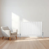 Radiateur plat blanc à 1 panneau, 600 x 910 mm, installé sur un mur clair, avec un sol en bois et un fauteuil moderne à côté