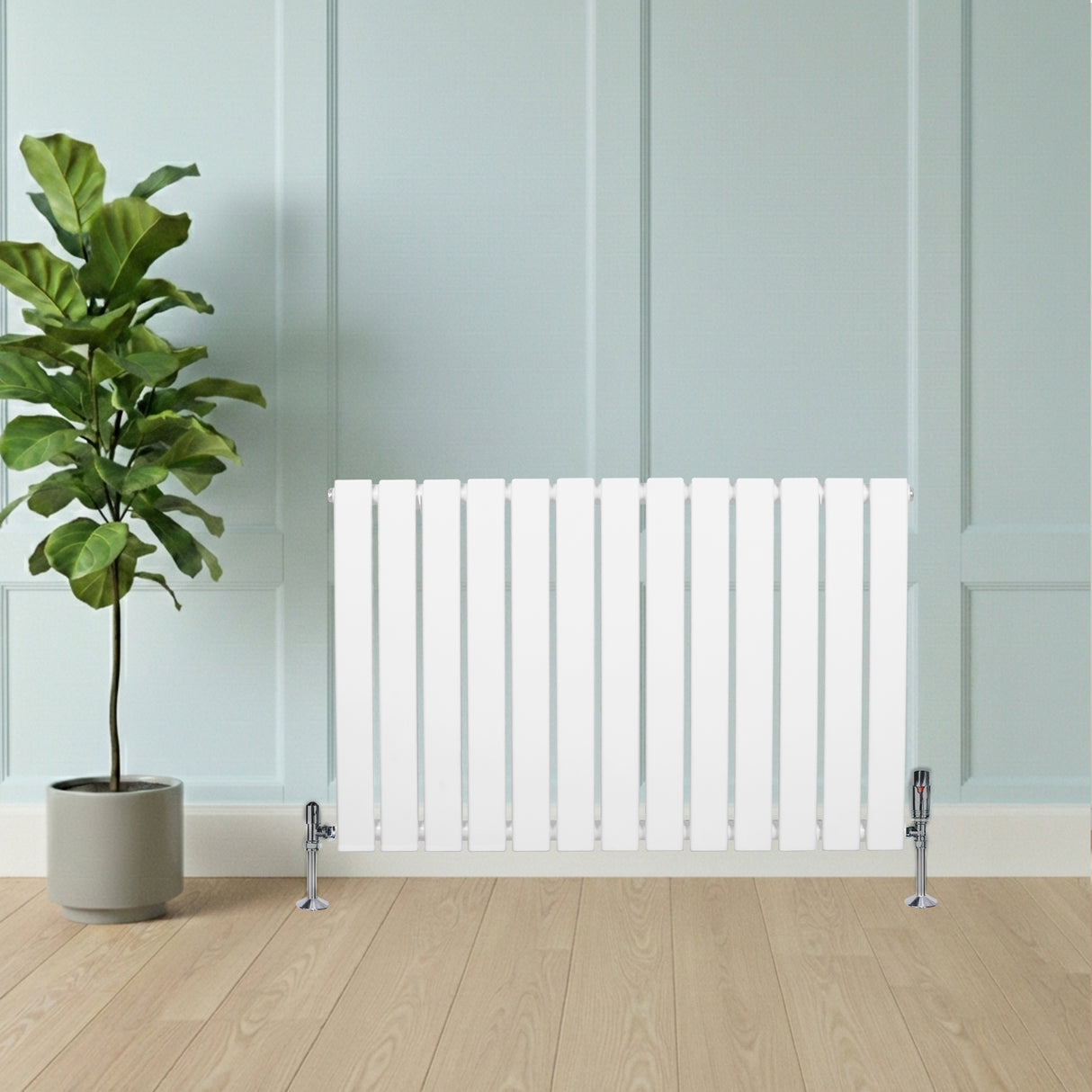 Radiateur plat blanc à un panneau, 600 x 910 mm, avec vannes, posé sur un sol en bois, à côté d'une plante verte dans un pot beige