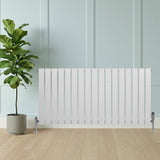 Radiateur plat blanc à un panneau, dimensions 600 x 1190 mm, installé contre un mur avec un pot de plante verte à côté sur un sol en bois clair