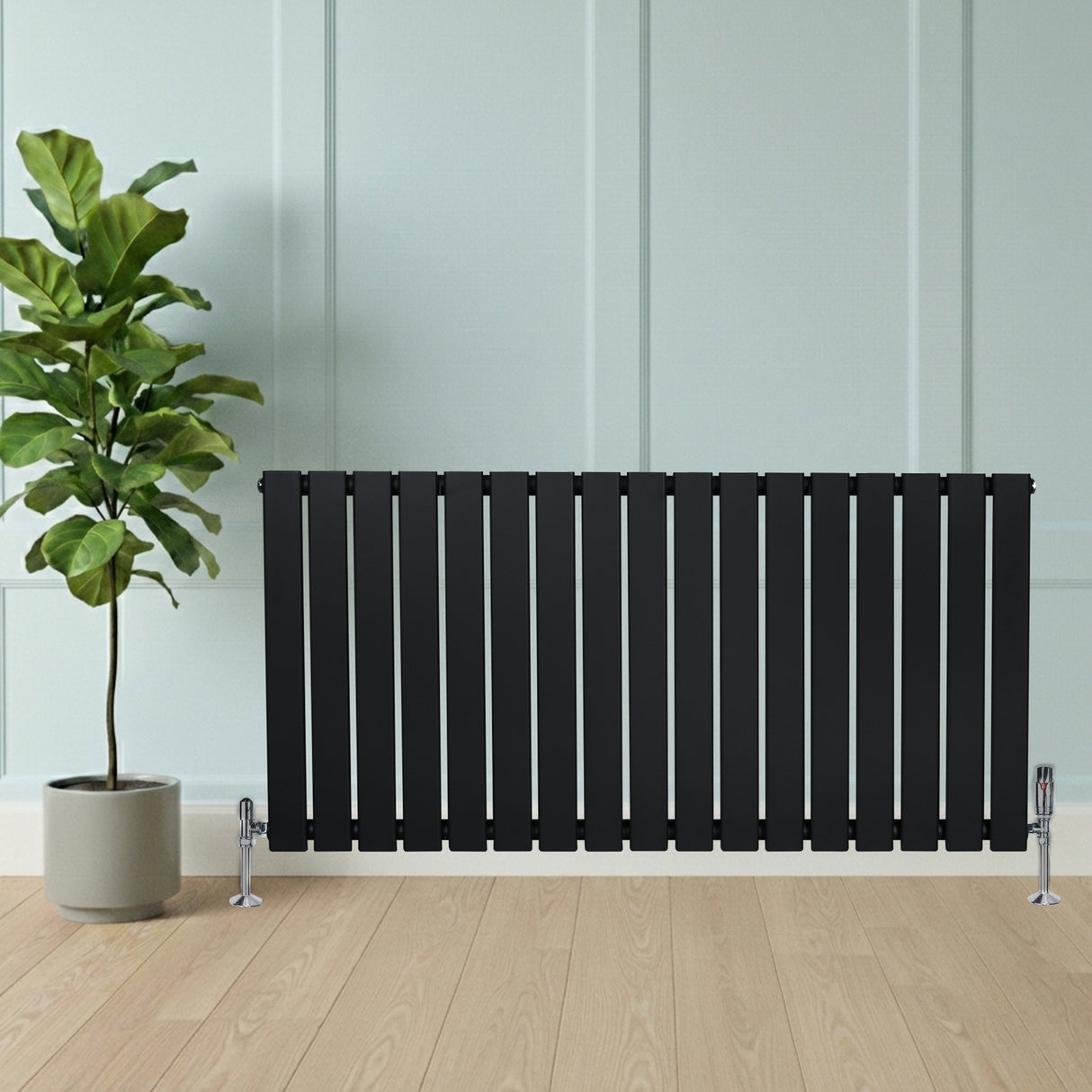 Radiateur plat noir à un panneau, 600 x 1190 mm, installé près d'une plante verte dans un intérieur moderne avec un sol en bois clair