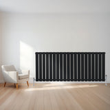 Radiateur plat noir à 1 panneau, 600 x 1400 mm, installé sur un mur clair, avec un sol en bois et un fauteuil moderne à côté