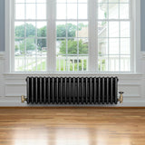 Radiateur traditionnel noir à 4 colonnes, 300 x 1010 mm, installé sous une fenêtre, avec des robinets en laiton et un sol en bois clair