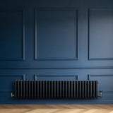 Radiateur traditionnel à 4 colonnes gris anthracite, installé contre un mur bleu, avec un design élégant et des finitions lisses