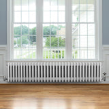 Radiateur traditionnel à 4 colonnes blanc, 300 x 1505 mm, installé sous une fenêtre, avec un sol en bois clair et un cadre lumineux