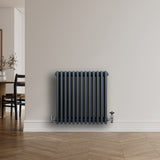 Radiateur traditionnel à 4 colonnes gris anthracite, finition lisse, installé sur un mur clair, avec un sol en bois chaleureux