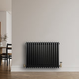 Radiateur traditionnel noir à 4 colonnes, 600 x 785 mm, installé contre un mur, avec des robinets en laiton et un sol en bois clair